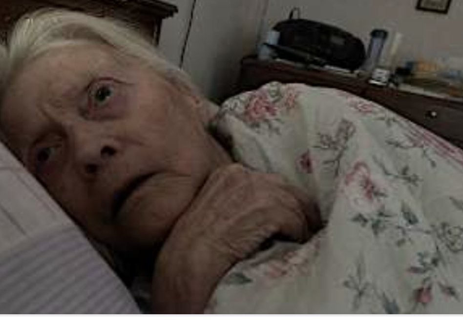 An elderly woman lying in bed looking frightened and lost